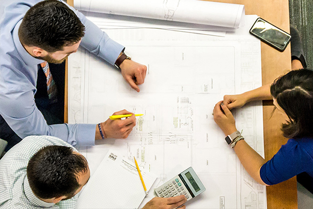Otero Homes build team consults over blueprints on pricing & budget of home